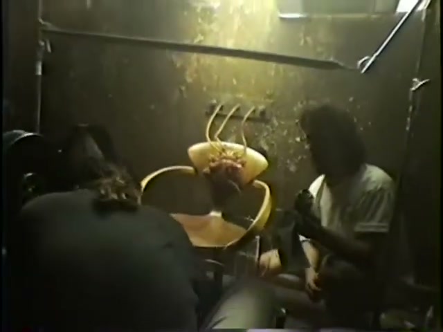Two crew members work on the mechanical heart prop mounted on a wooden chair on the Closer set.