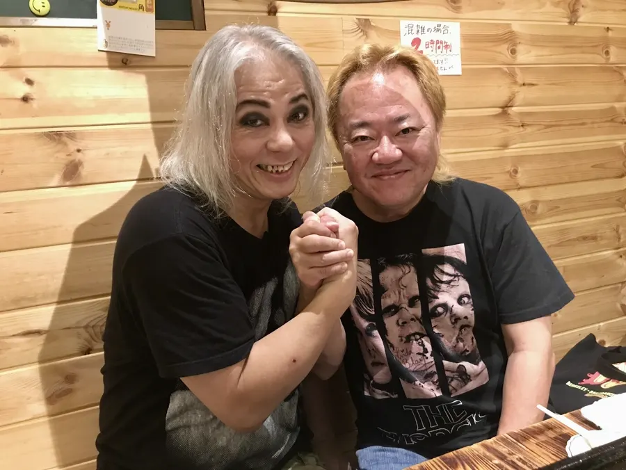 Screaming Mad George and Shinichi Wakasa stand arm in arm at an Osaka restaurant.