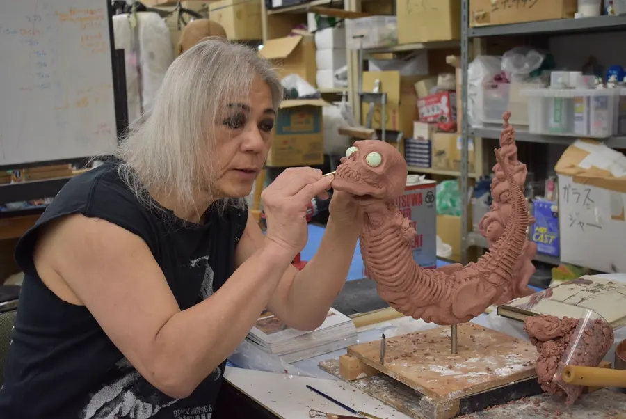 Screaming Mad George uses a small tool to detail the eye of a ribbed clay creature at his Osaka workbench.