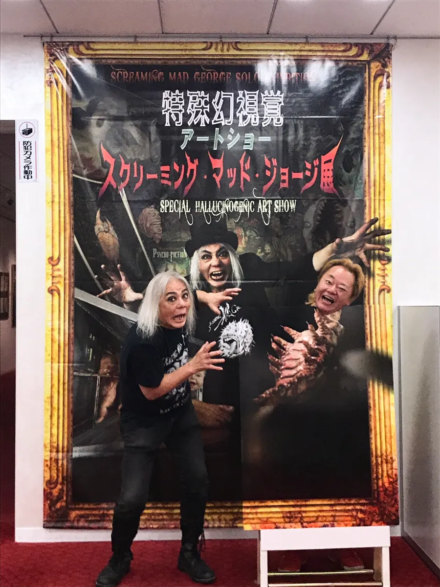 Screaming Mad George poses in front of a banner for his Special Hallucinogenic Art Show in Osaka.